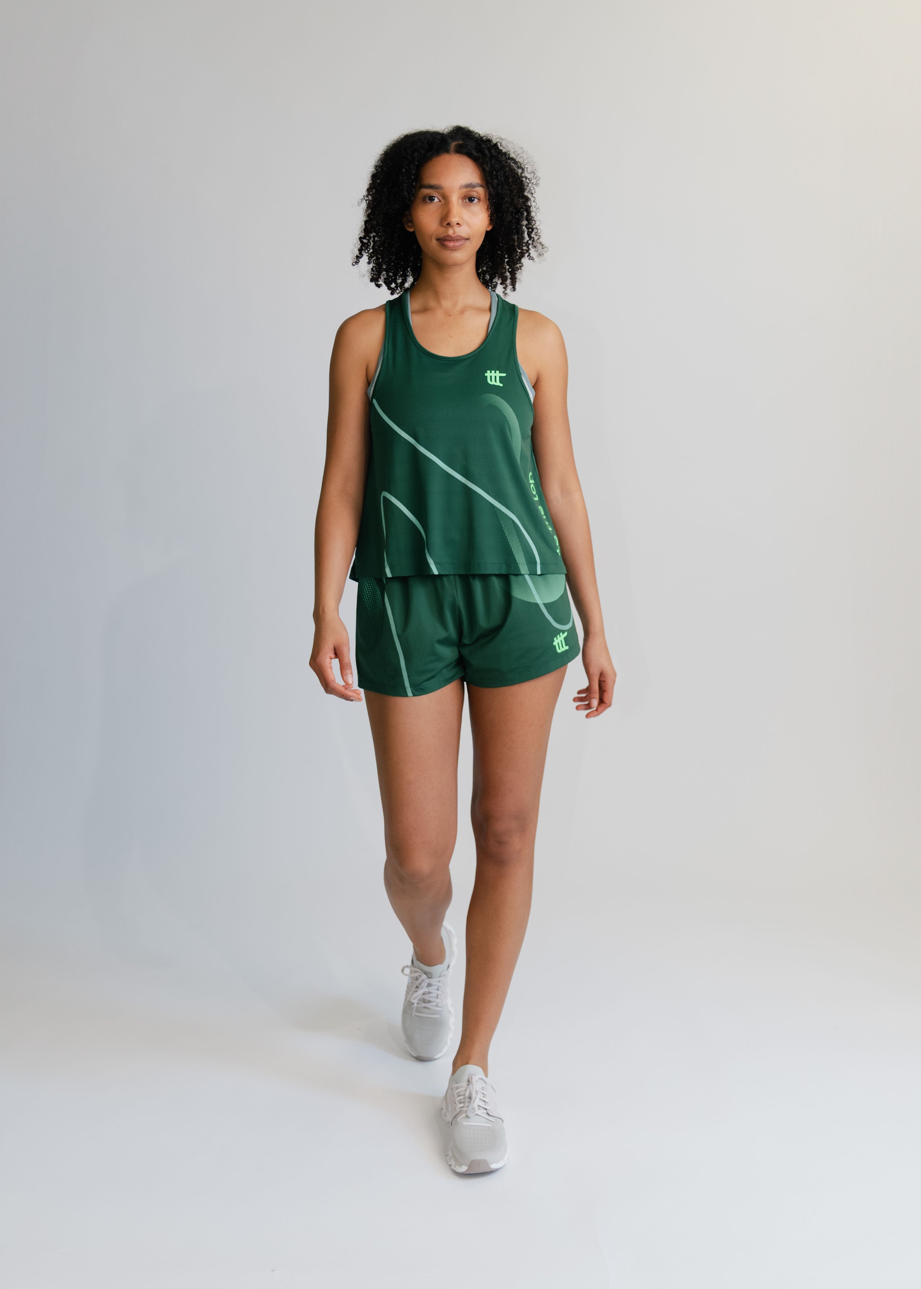 Model trägt das grüne Pace Tank Top als Teil eines modischen Athleisure-Outfits